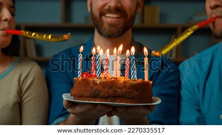 Cropped view caucasian adult happy bearded man celebrate birthday at home diverse african caucasian friends congratulate male with festive cake blowing party whistles make surprise annual tradition Royalty-Free Stock Photo #2270335517