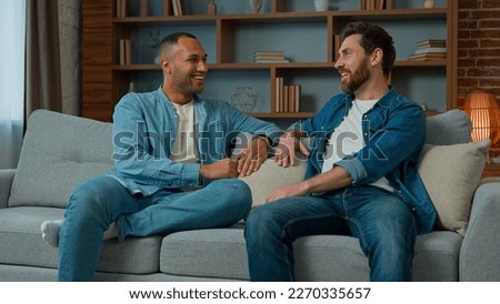 Two diverse 30s men businessmen talking at home on sofa multiracial friends companions african american caucasian ethnicity fellows brothers discussing plans friendly talk male dialogue conversation Royalty-Free Stock Photo #2270335657