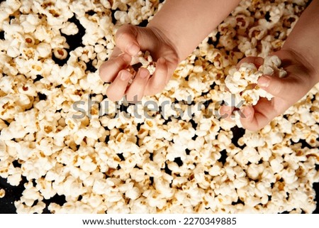 Children's hands are picking up popcorn. Flat lay . The concept of a birthday, party, holiday, home leisure. Copy space for your product. Popcorn texture or background.