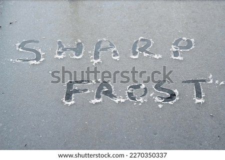 The words sharp frost scraped into ice on glass. 