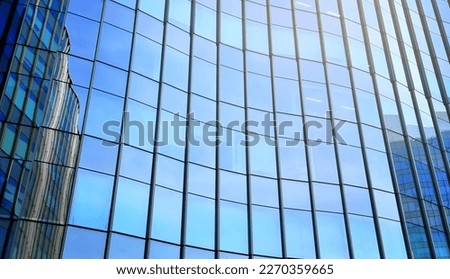 glass buildings reflecting with bright blue sky used as background. modern office building exterior, blue toned image for commercial, business, corporate concept. modern curtain wall.