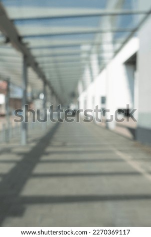Blurred background with a connecting walkway with a glass roof on a sunny day