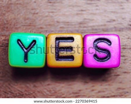 Selective focus. The word 'YES' is written in plastic cuboid letters on a wooden background. Concept of success, success, agree, ready, excited.