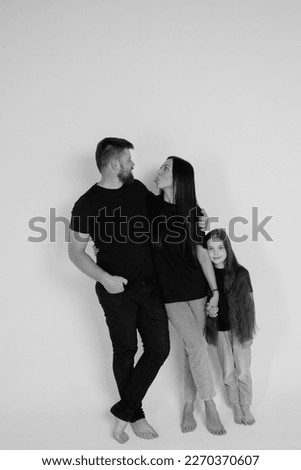 Young beautiful family - dad, mom and daughter in jeans and T-shirts on a white background