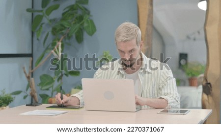 Graphic Designer Working on Laptop and Graphic Tablet