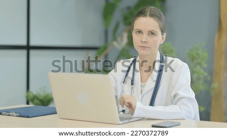 Young Female Doctor Looking at Camera while using Laptop