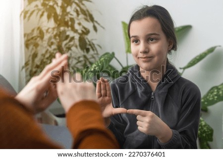 Small Caucasian teen girl child do articulation exercises with caring mother or teacher at home. Little kid pronounce sounds speak talk with tutor or coach, engaged in voice pronunciation together Royalty-Free Stock Photo #2270376401