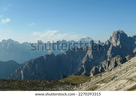 Panoramic view on Italian Dolomites. Endless, high and sharp mountains from each side. The peaks are shrouded in morning haze. Narrow pathway going along the mountain slope. Remote and isolated place Royalty-Free Stock Photo #2270393315