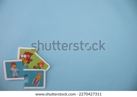 Educational puzzles with pictures of firemen, fire trucks, space shuttles and astronauts scattered across the lower left of the blue background.