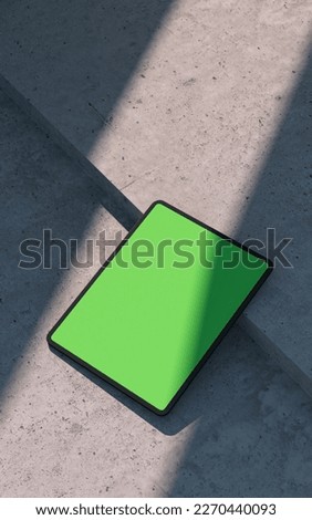 Mockup of black tablet device, lay on a concrete surface, outdoor. Clipping path for display included. 3D rendering. 3D Illustration