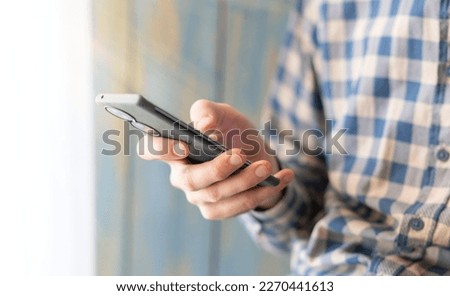 Close-up image of male hands using smartphone at night on city shopping street, searching or social networks concept