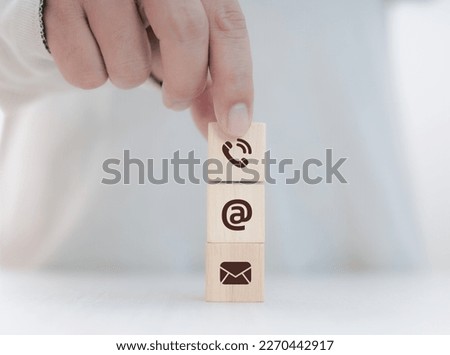 Contact us concept, hand holding wooden blocks and communication icons