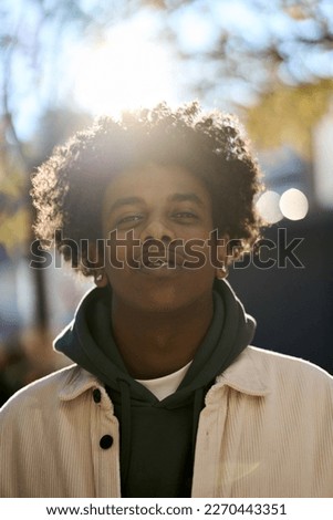 Confident cool young African American guy model standing at sunny city street style. Stylish ethnic rebellious hipster gen z teen boy looking at camera outdoors in park, close up vertical portrait. Royalty-Free Stock Photo #2270443351