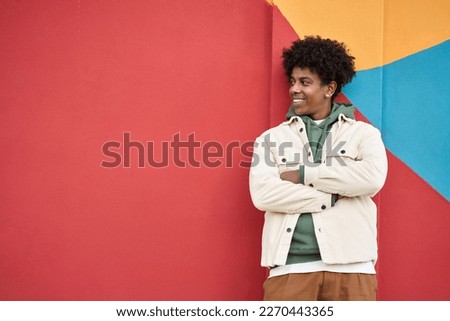Young happy African American teen guy isolated on bright colors wall background. Smiling stylish cool ethnic generation z teenager student model standing looking away at copy space for advertising. Royalty-Free Stock Photo #2270443365