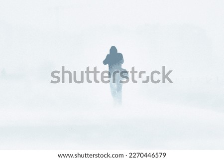 A snowstorm in the city. People are walking down the street during a snowstorm. Strong wind and snowfall. Arctic climate. Royalty-Free Stock Photo #2270446579