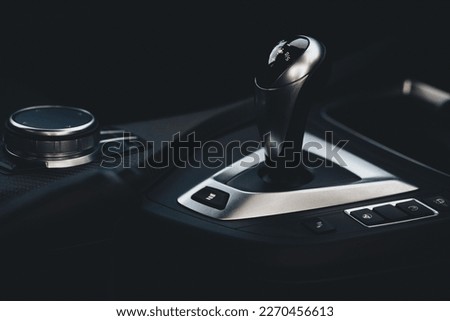 Close up photo of a car gear stick manual transmission gear changer centre console automatic semi automatic vehicle. Automobile new car black interior dashboard leather. 