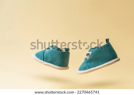 Pair of flying baby shoes with laces on yellow background. Childhood concept with levitation effect and copy space Royalty-Free Stock Photo #2270465741