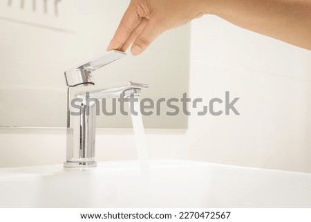 close up Woman open pull chrome faucet washbasin to washing hand soap for corona virus at run water tap. push off water running drop off. Bathroom interior background with sink basin faucet tap. Royalty-Free Stock Photo #2270472567