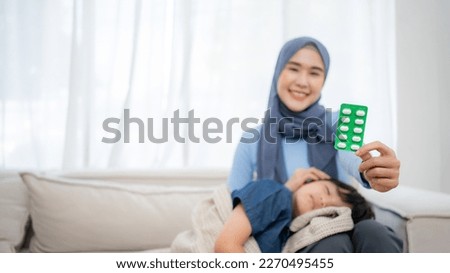 Closeup photo of caring Asian mother holding head on sick son forehead. Showing a medicine pack.
