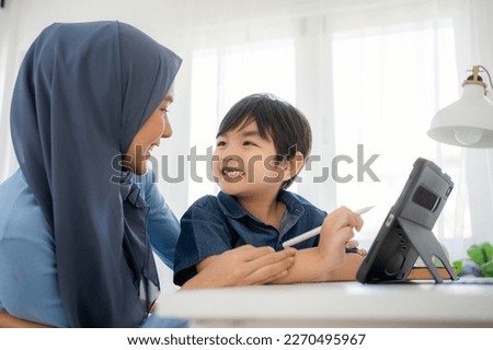 Mother and son reading E-book and teaching for painting using application together at home.
