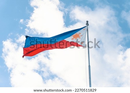 waving philippine flag in a pole with clouds and blue sky background