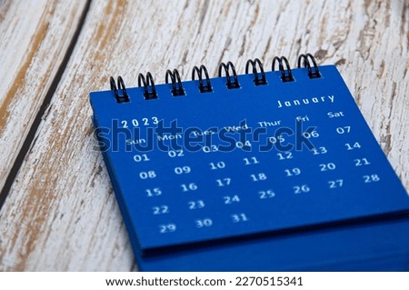 January 2023 blue table calendar on wooden cover background. Calendar concept