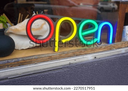 Rainbow colored neon sign that says open, red, yellow, green, and blue