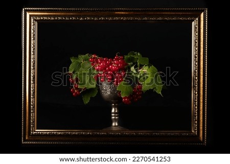 In an old frame, a silver glass with red currants. Still life in the old style of the last century.