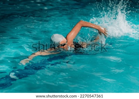 Young Woman Swimming in the Indoor Pool.