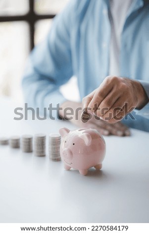 Person with pile of coins and piggy bank, money saving concept for future use and financial stability, salary management, personal finance, investment savings. Royalty-Free Stock Photo #2270584179