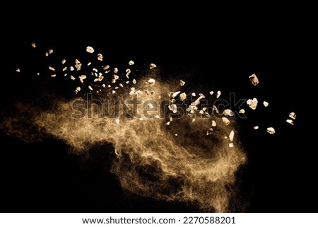 Split debris of  stone exploding with brown powder against black background. Royalty-Free Stock Photo #2270588201
