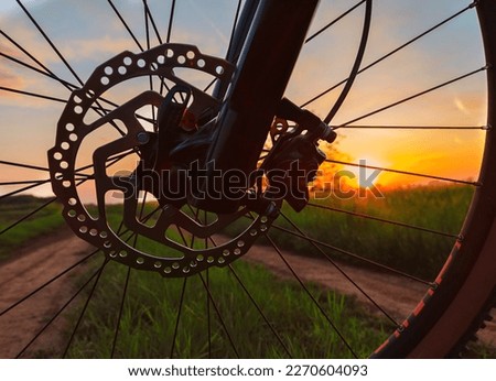 Bicycle wheel on dirt path and setting sun in the background 