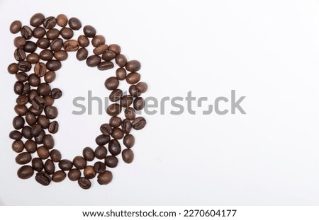 D is a capital letter of the English alphabet made up of natural roasted coffee beans that lie on a white background. Plenty of space to put text or pictures, top view and studio photography.