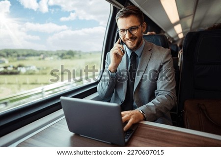 Handsome middle age businessman using his laptop computer while traveling with high-speed train. Modern and fast travel concept. Royalty-Free Stock Photo #2270607015