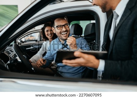 Middle age couple choosing and buying car at car showroom. Car salesman helps them to make right decision. Royalty-Free Stock Photo #2270607095