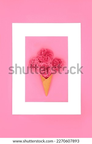 Surreal ice cream cone with red summer rose flowers and white frame on pink background. Abstract nature floral food gift concept.