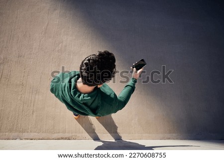 Overhead picture of a man using smartphone on city street wearing hooded sports sweatshirt Royalty-Free Stock Photo #2270608755