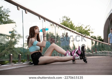 A long-haired brunette in shorts sits on a bridge.