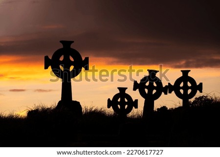 Silhouettes of gravestones with Celtic crosses at Cross Abbey graveyard at dusk, Mullet Peninsula, County Mayo, Ireland