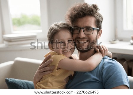 Positive young father hugging little kid girl hugging with face touch, smiling, laughing, looking at camera, enjoying family bonding, parent and child relationship, family leisure, fatherhood