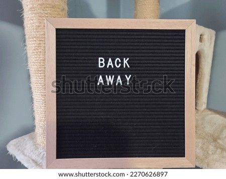 A sign saying back away. The felt sign has removable letters than can be moved around to make whatever words or saying one wants. 