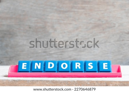 Tile alphabet letter with word endorse in red color rack on wood background