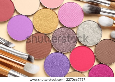 Different beautiful eye shadows and makeup brushes on beige background, flat lay Royalty-Free Stock Photo #2270667757