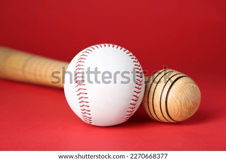 Wooden baseball bat and ball on red background, closeup. Sports equipment