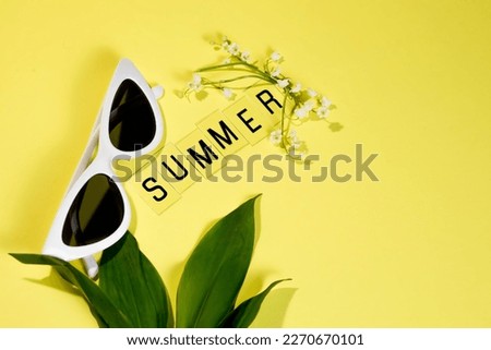 Summer layout of flowers, leaves, glasses and text with the inscription summer on a pastel yellow background. Summer screensaver