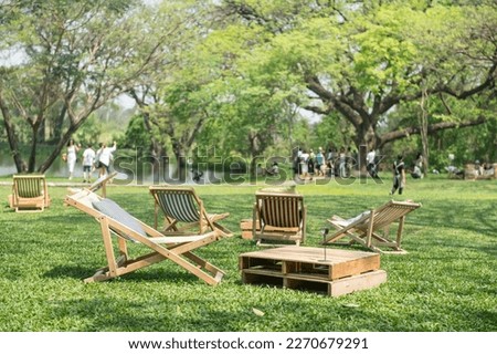 Sunbeds and wooden table on green grass in spring garden of outdoor cafe and restaurant.