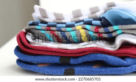 a stack of striped multi-colored children's socks lying on a light table close-up, home clothes in detail and bright colors, part of the children's wardrobe