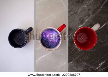 Three coffee cups top view, the middle cup has a cosmos with stars and the other two are empty, decorative background