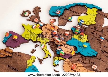 map of europe with flags, lots of round metal buttons with different flags of countries on the map of europe, wooden three-dimensional map of the world on a white background, politics, international Royalty-Free Stock Photo #2270696433