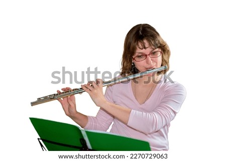A young female flautist plays a wind instrument flute and looking at the notes, isolated on a white background Royalty-Free Stock Photo #2270729063
